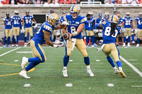 Winnipeg Blue Bombers quarterback Zach Collaros hands the ball off to Winnipeg Blue Bombers running back Brady Oliveira.